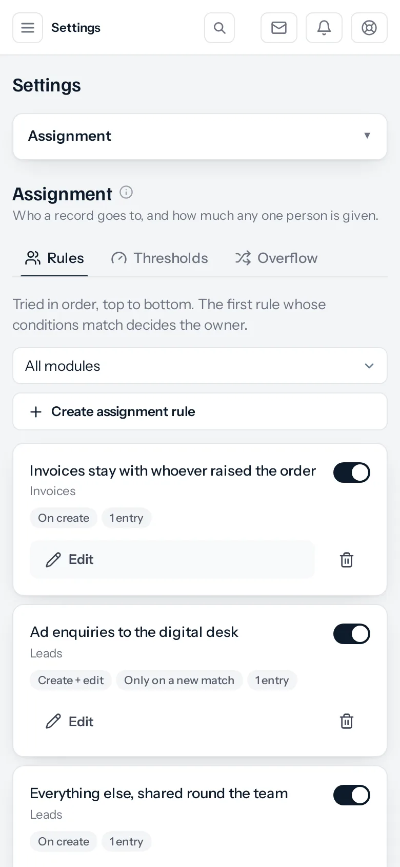 The Assignment screen on a phone. Settings sits in a dropdown at the top, then the Rules, Thresholds and Overflow tabs, an All modules filter and a Create assignment rule button. Each rule is a card: its name, the module underneath, then pills reading On create, or Create + edit and Only on a new match, and 1 entry, with an Edit button, a bin and an on-off switch.